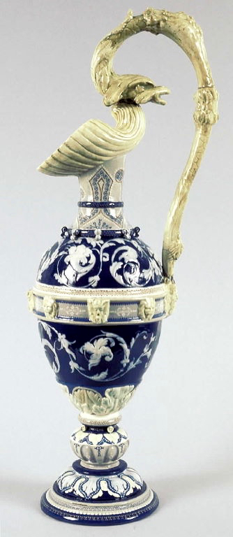 Aiguière en faïence bleu cobalt et crème, corps ovoïde orné de rinceaux en relief et de mascarons, anse sculptée