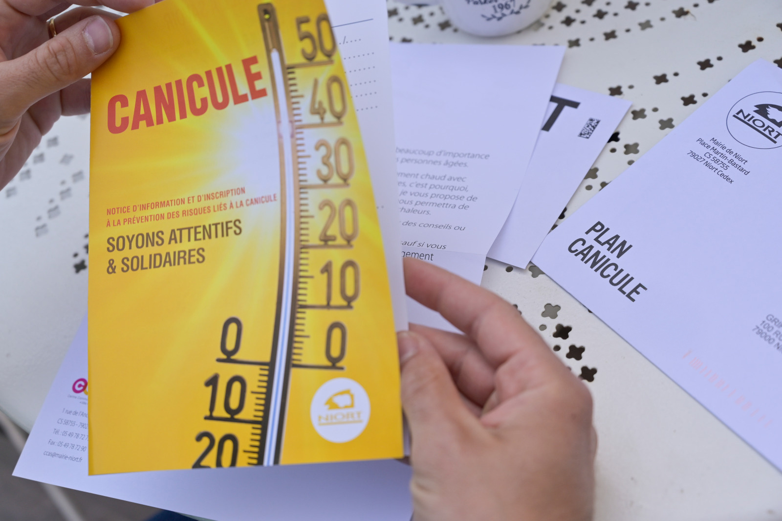 Brochure Plan Canicule de la Ville de Niort tenue en main, avec thermomètre et slogan « Soyons attentifs & solidaires »
