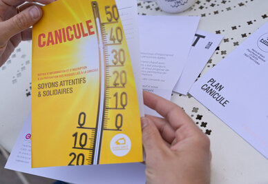 Brochure d'information « Plan Canicule – Soyons attentifs & solidaires » tenue en mains, thermomètre à 50 °C illustré en couverture