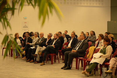 Participants assis en rangs lors d'une conférence institutionnelle, attentifs à une intervention hors champ