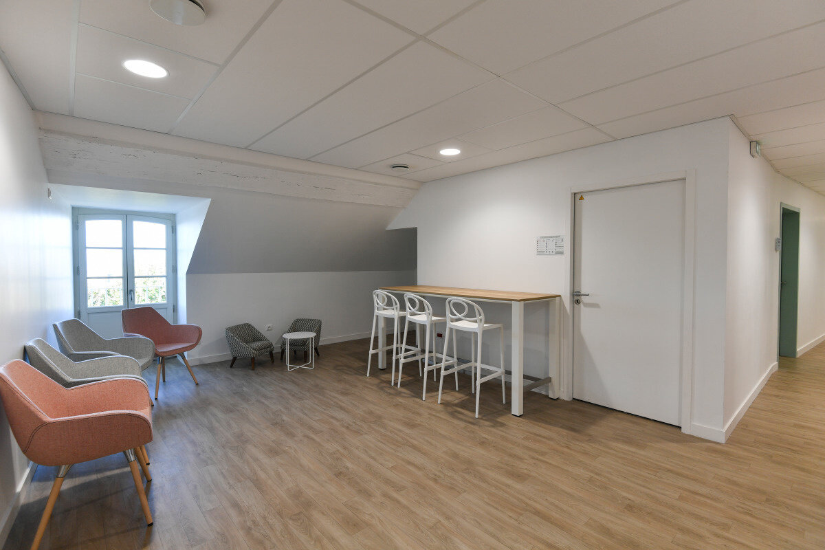 Novembre 2019 Salle de détente du Conservatoire avec fauteuils colorés, table haute et tabourets blancs sur parquet clair