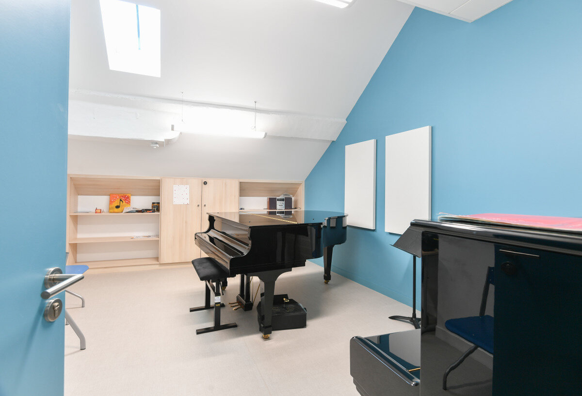 Novembre 2019 Salle de cours du Conservatoire avec piano à queue noir, pupitre, étagères en bois et panneaux acoustiques muraux