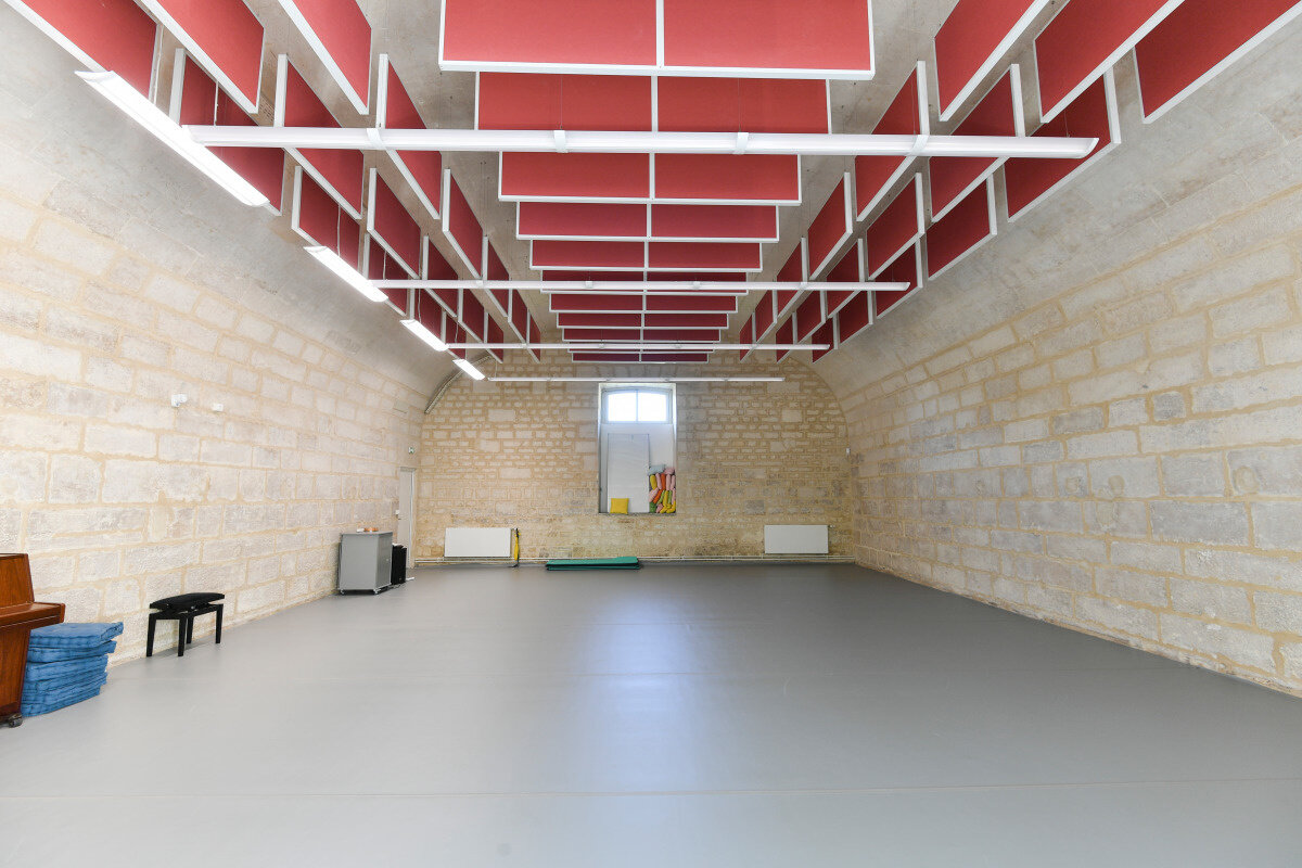 Novembre 2019 Salle de répétition aux murs en pierre de taille, sol souple gris et plafond acoustique à panneaux rouges