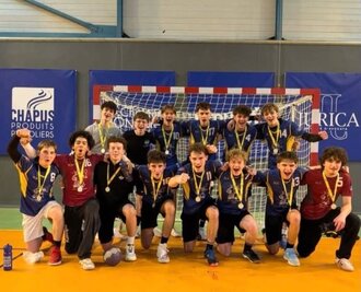 Les joueurs en tenue bleue arborent leurs médailles et célèbrent en groupe devant un but de handball.