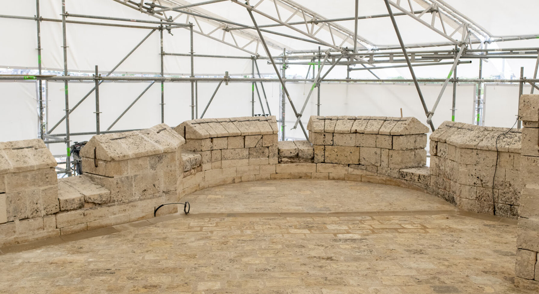 Vestiges archéologiques en pierres sous une structure de chantier temporaire au Donjon de Niort