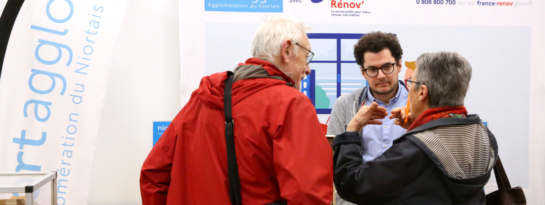 Stand Niort Agglo / France Rénov' lors d'un salon : un conseiller renseigne deux visiteurs sur leurs projets de rénovation