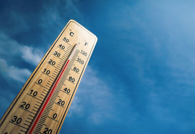 ThermomÚtre en bois affichant plus de 33 °C sur fond de ciel bleu, évoquant une vague de chaleur