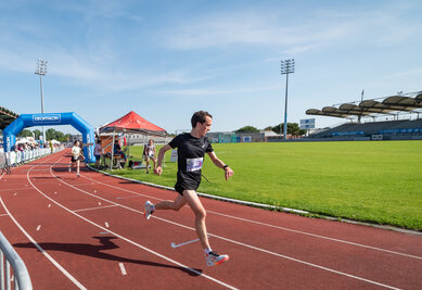 Coureur en compétition sur la piste d'athlétisme du stade