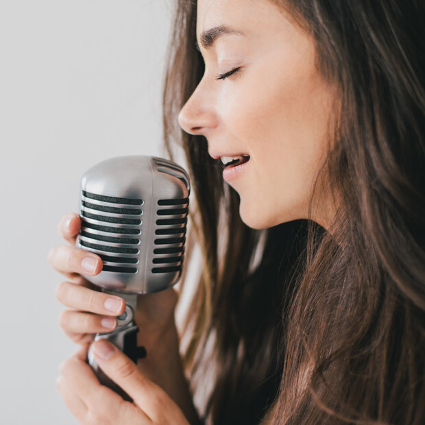 Chanteuse les yeux fermés tenant un micro vintage, dans une posture d'interprétation vocale intense