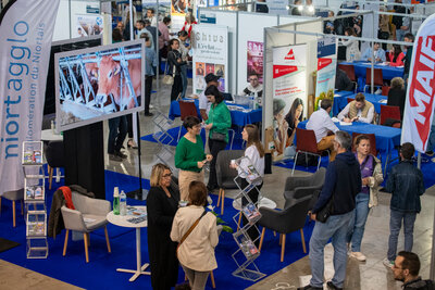 Hall d'exposition avec stands d'employeurs — Niort Agglo, MAIF, Shiva — et visiteurs en entretien