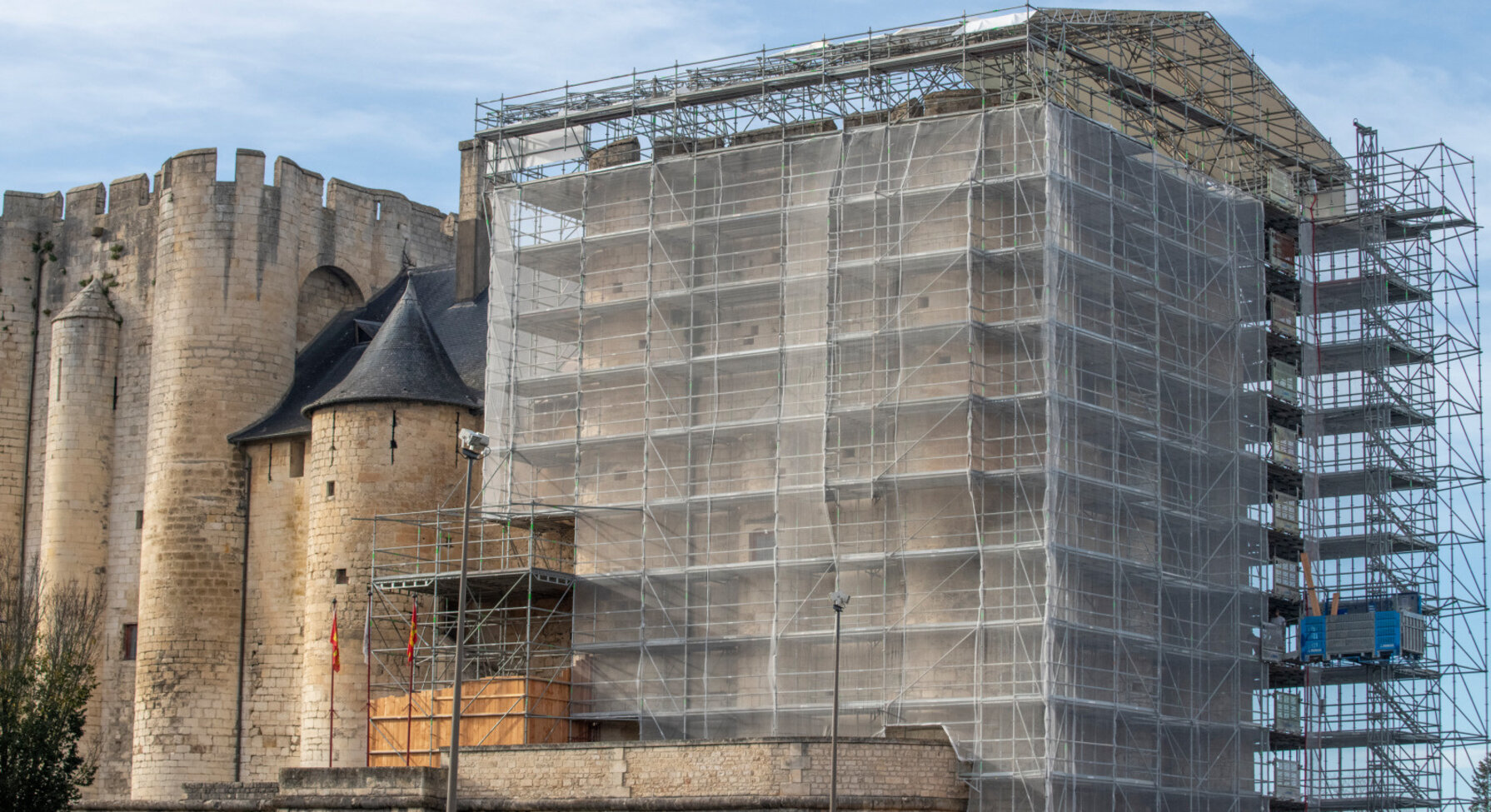 Tour nord du Donjon entièrement habillée d'un échafaudage métallique et de filets blancs,