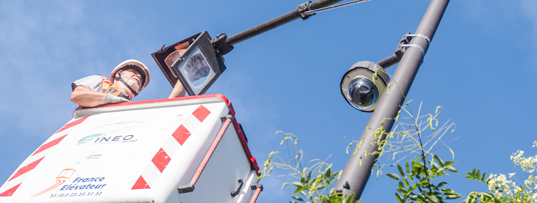 Technicien en nacelle élévatrice réalisant une intervention de maintenance sur un poteau d'éclairage public