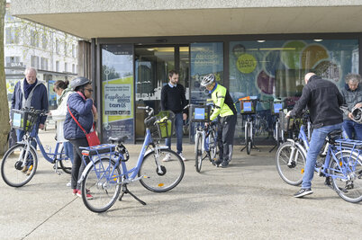 Usagers récupérant leurs vélos tanlib en location annuelle devant l'agence, accompagnés par un agent en gilet jaune