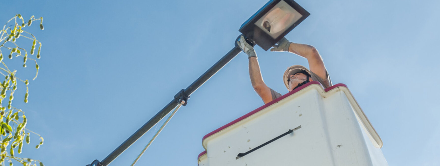 Technicien casqué en nacelle élévatrice procédant à l'installation d'un luminaire d'éclairage public