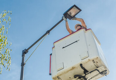 Technicien casqué en nacelle élévatrice procédant à l'installation d'un luminaire d'éclairage public