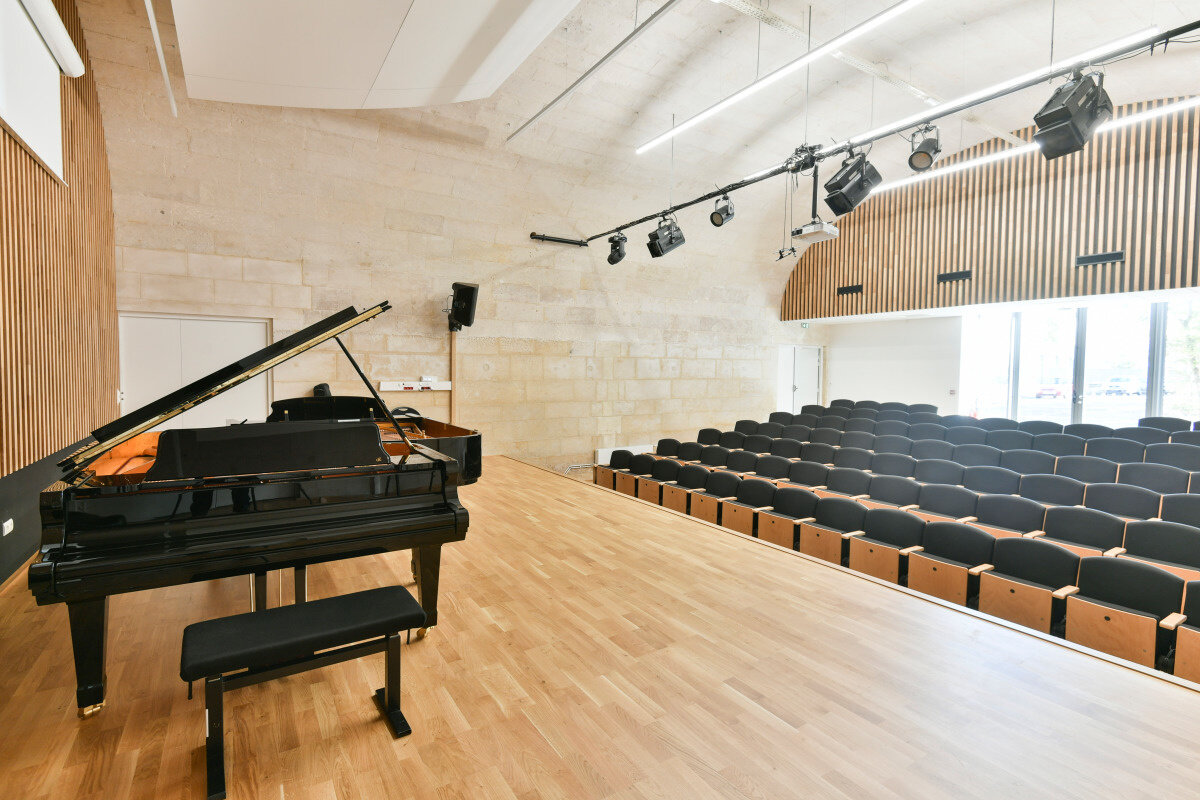 Novembre 2019 Salle de concert du conservatoire avec piano à queue sur scène en parquet, gradins vides et projecteurs de scène