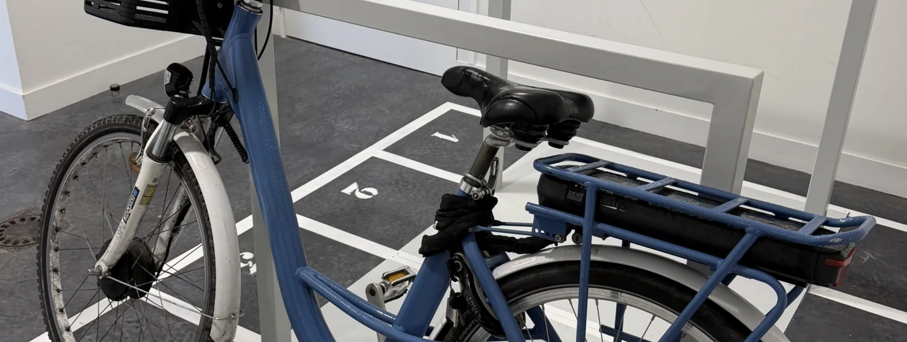 Vélo à assistance électrique stationné sur un emplacement numéroté dans le local de stationnement sécurisé